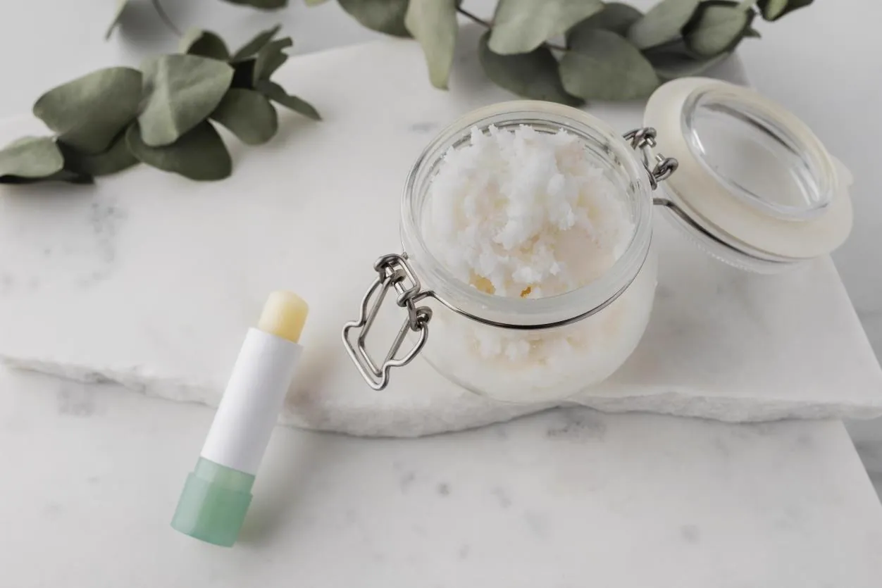 Lip balm stick and jar of balm base on a marble surface